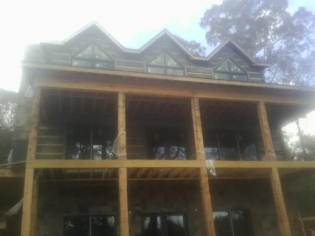 Dormers and porch framing on a large log home under construction — Roof Coating work by our crew in Jericho
