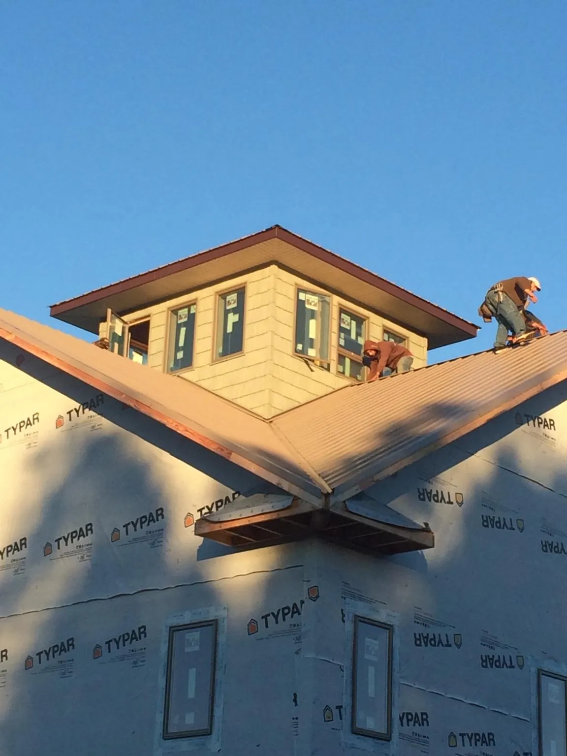Roofers working around a rooftop cupola on a new metal roof at sunset — Roof Waterproofing in Jericho by Roofing Brothers